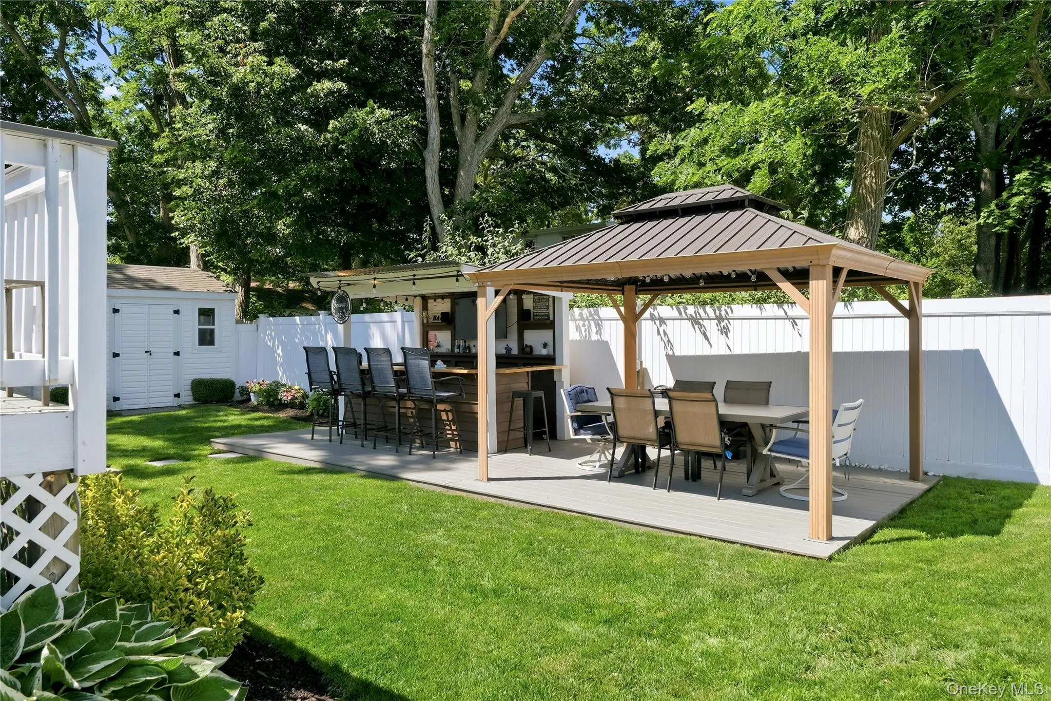Expansive backyard featuring a gazebo-covered outdoor dining area and a built-in bar with seating Expansive backyard featuring a gazebo-covered outdoor dining area and a built-in bar with seating