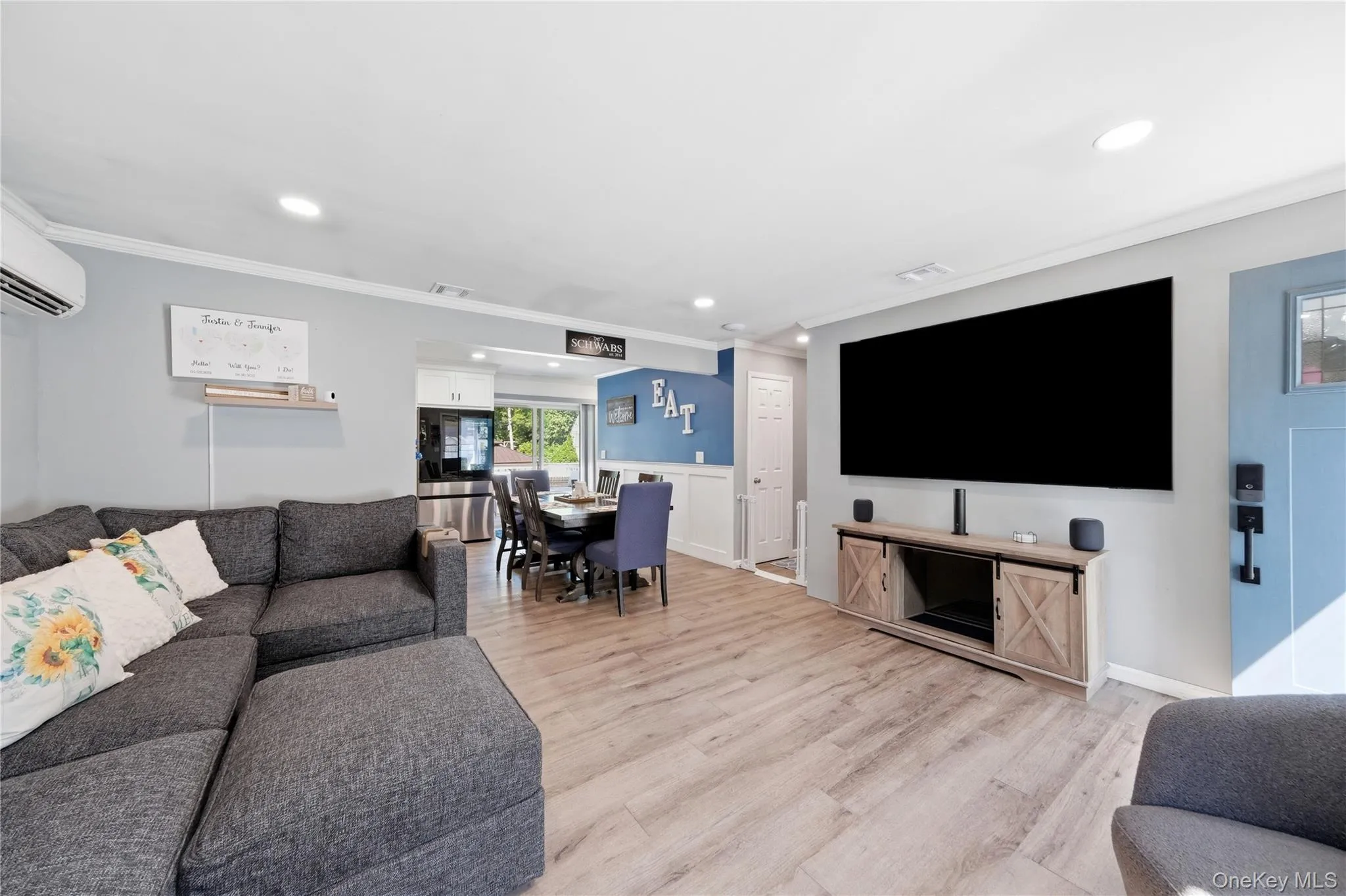 Open-concept living area featuring wood-finish flooring, recessed lighting, and crown molding Open-concept living area featuring wood-finish flooring, recessed lighting, and crown molding