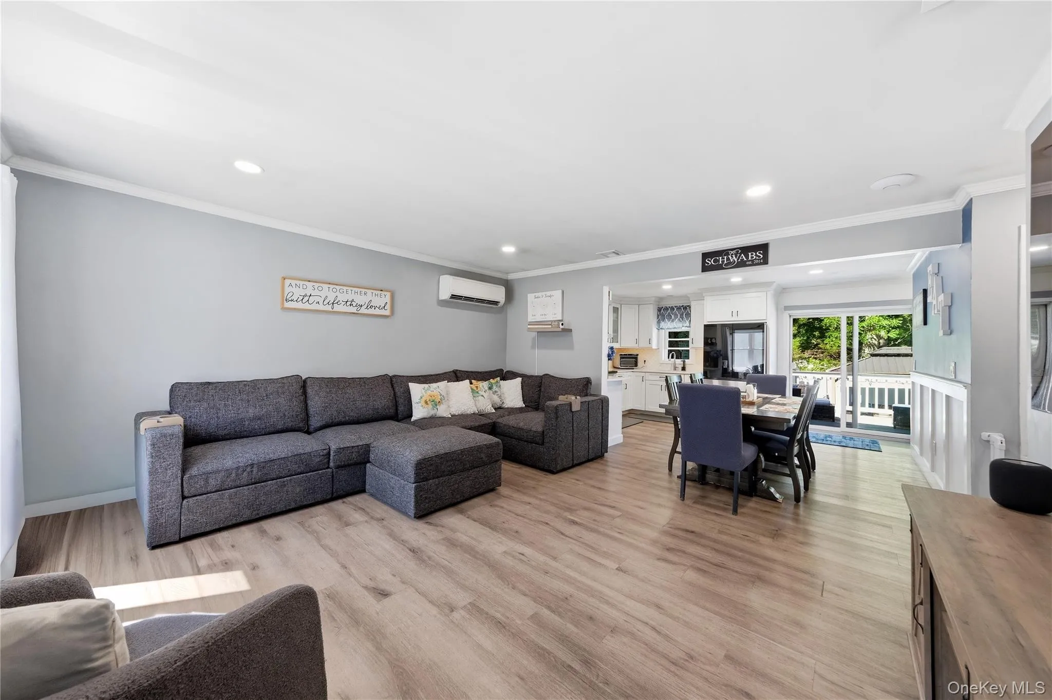 Open-concept living area featuring wood-finish flooring, recessed lighting, and crown molding Open-concept living area featuring wood-finish flooring, recessed lighting, and crown molding
