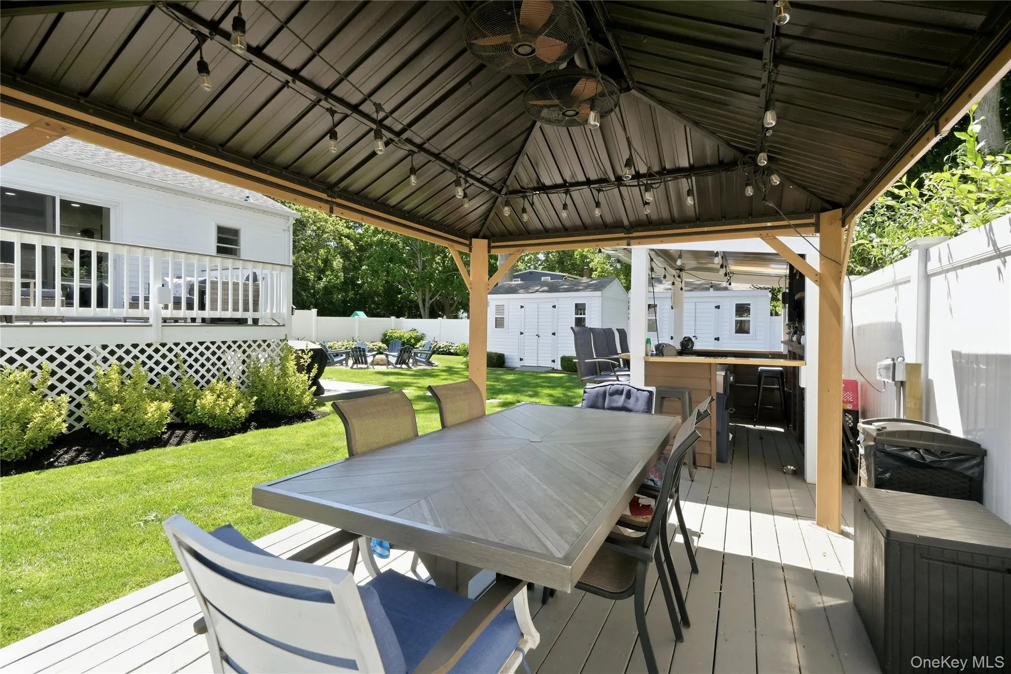 Covered patio with string lights, dual ceiling fans, and a built-in outdoor bar Covered patio with string lights, dual ceiling fans, and a built-in outdoor bar