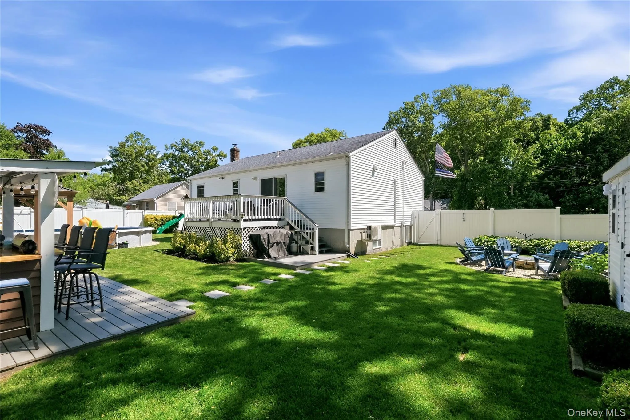 Expansive backyard featuring a manicured lawn, a multi-level deck, a built-in outdoor bar with pergola, a fire pit area, and a privacy fence Expansive backyard featuring a manicured lawn, a multi-level deck, a built-in outdoor bar with pergola, a fire pit area, and a privacy fence