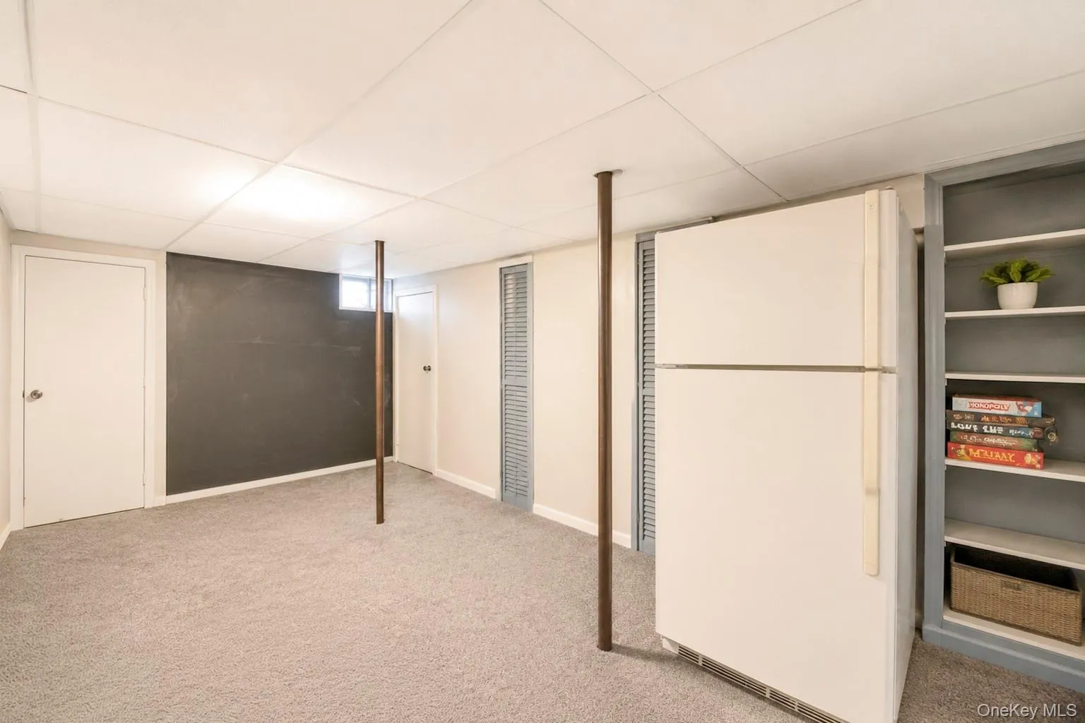 Carpeted room featuring a drop ceiling, white paneled doors, and a chalkboard accent wall Carpeted room featuring a drop ceiling, white paneled doors, and a chalkboard accent wall
