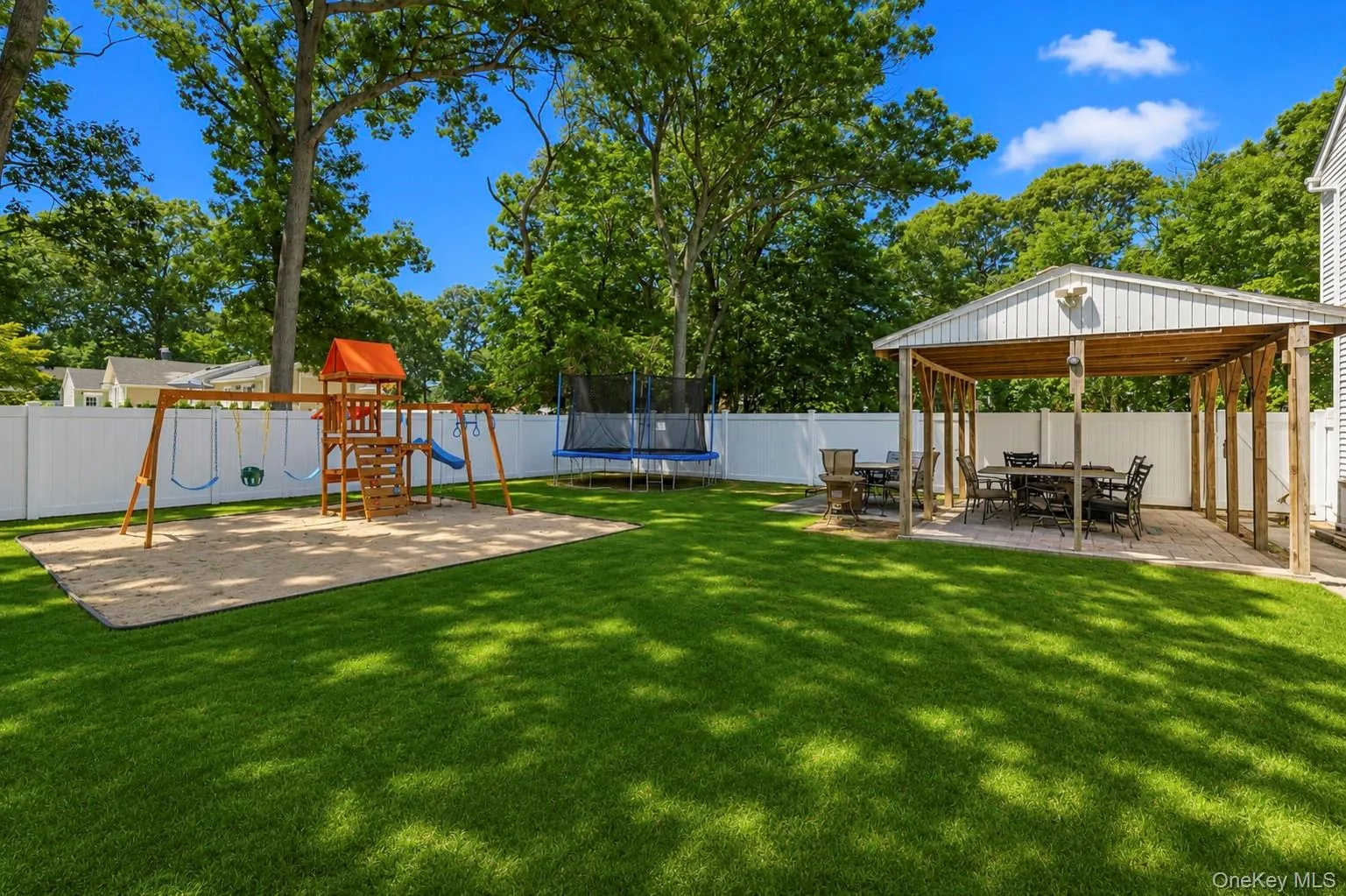 Expansive backyard featuring a lush green lawn, full privacy fencing, and mature trees Expansive backyard featuring a lush green lawn, full privacy fencing, and mature trees