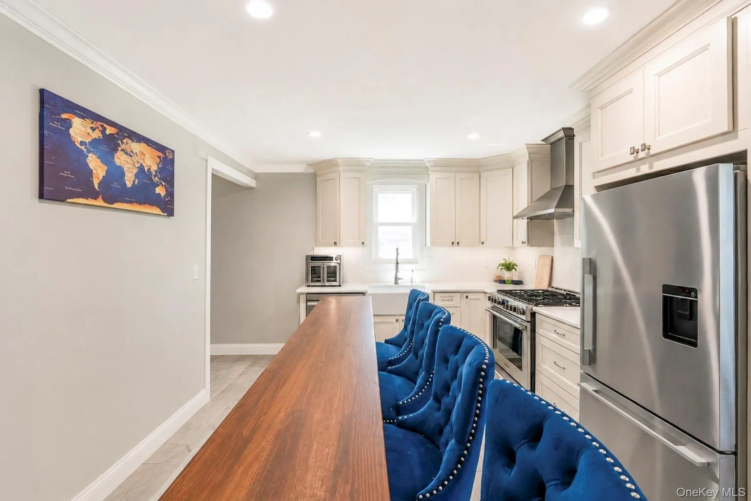Open-concept kitchen featuring an eat-at counter with wood-finish top, white shaker cabinetry, stainless steel appliances, and recessed lighting Open-concept kitchen featuring an eat-at counter with wood-finish top, white shaker cabinetry, stainless steel appliances, and recessed lighting