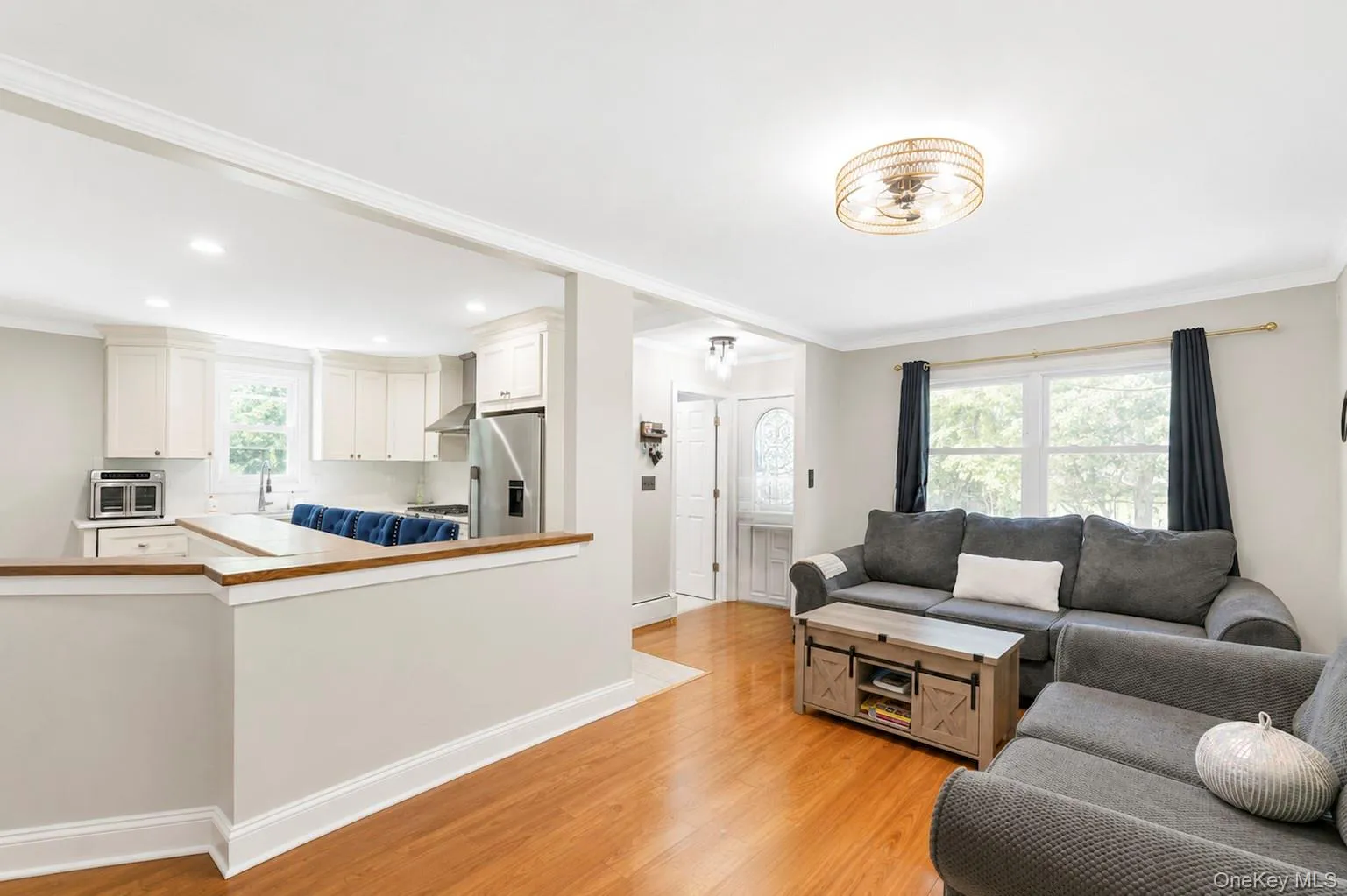 Living area featuring wood-finish flooring, a contemporary ceiling light fixture, and crown molding Living area featuring wood-finish flooring, a contemporary ceiling light fixture, and crown molding
