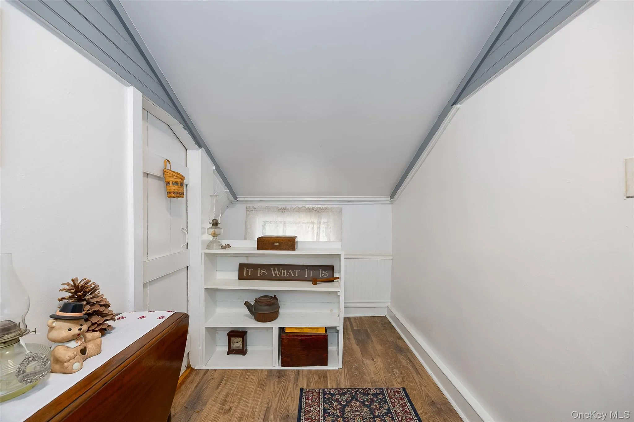 Hallway featuring dark wood-style flooring, wainscoting, and a decorative wall Hallway featuring dark wood-style flooring, wainscoting, and a decorative wall