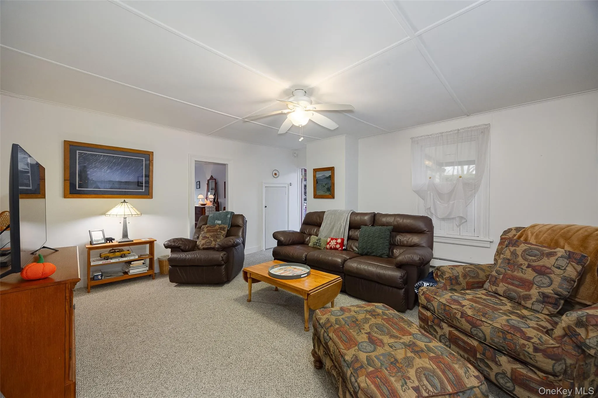 Carpeted living area with a ceiling fan Carpeted living area with a ceiling fan
