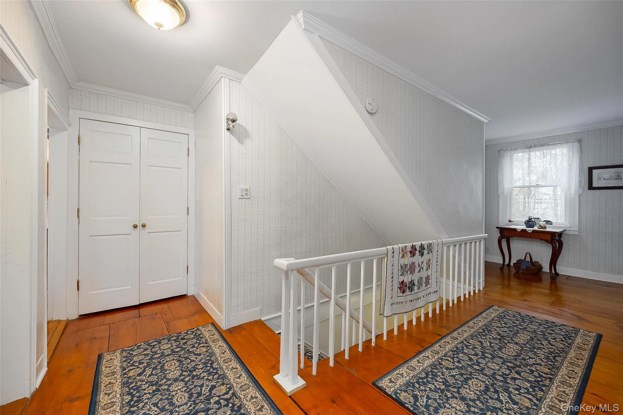 Hallway featuring crown molding, hardwood / wood-style flooring, wallpapered walls, and an upstairs landing Hallway featuring crown molding, hardwood / wood-style flooring, wallpapered walls, and an upstairs landing