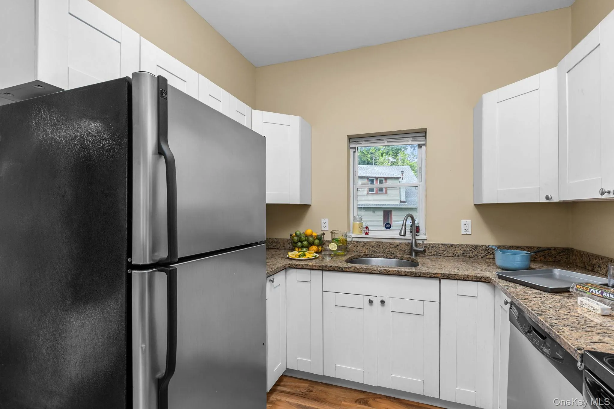 Kitchen featuring white soft-close cabinetry, granite-finish countertops, stainless steel sink with a gooseneck faucet, and wood-finish flooring. Kitchen featuring white soft-close cabinetry, granite-finish countertops, stainless steel sink with a gooseneck faucet, and wood-finish flooring.