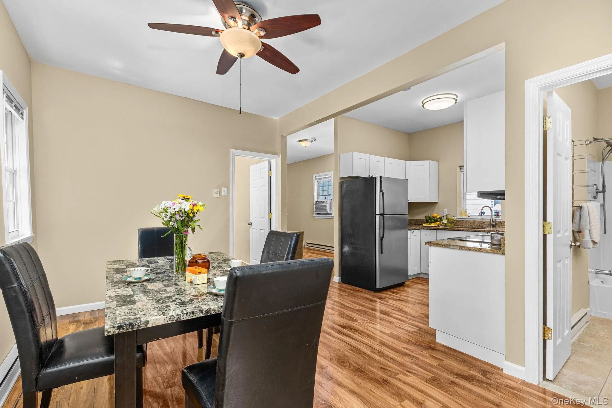 Open-concept living space featuring wood-finish flooring, a ceiling fan with integrated lighting, and neutral wall tones Open-concept living space featuring wood-finish flooring, a ceiling fan with integrated lighting, and neutral wall tones