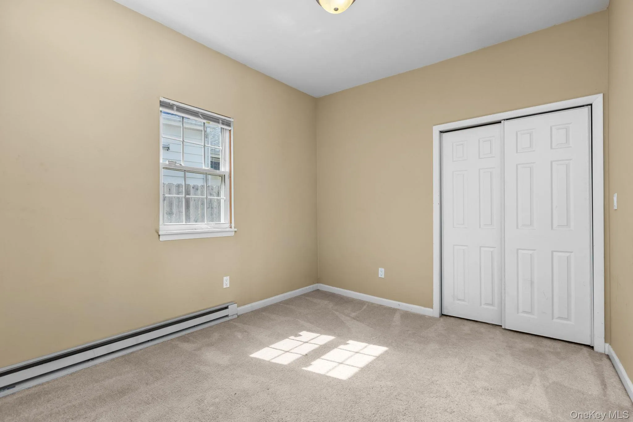 Carpeted room with a double-paned window and baseboard heating Carpeted room with a double-paned window and baseboard heating