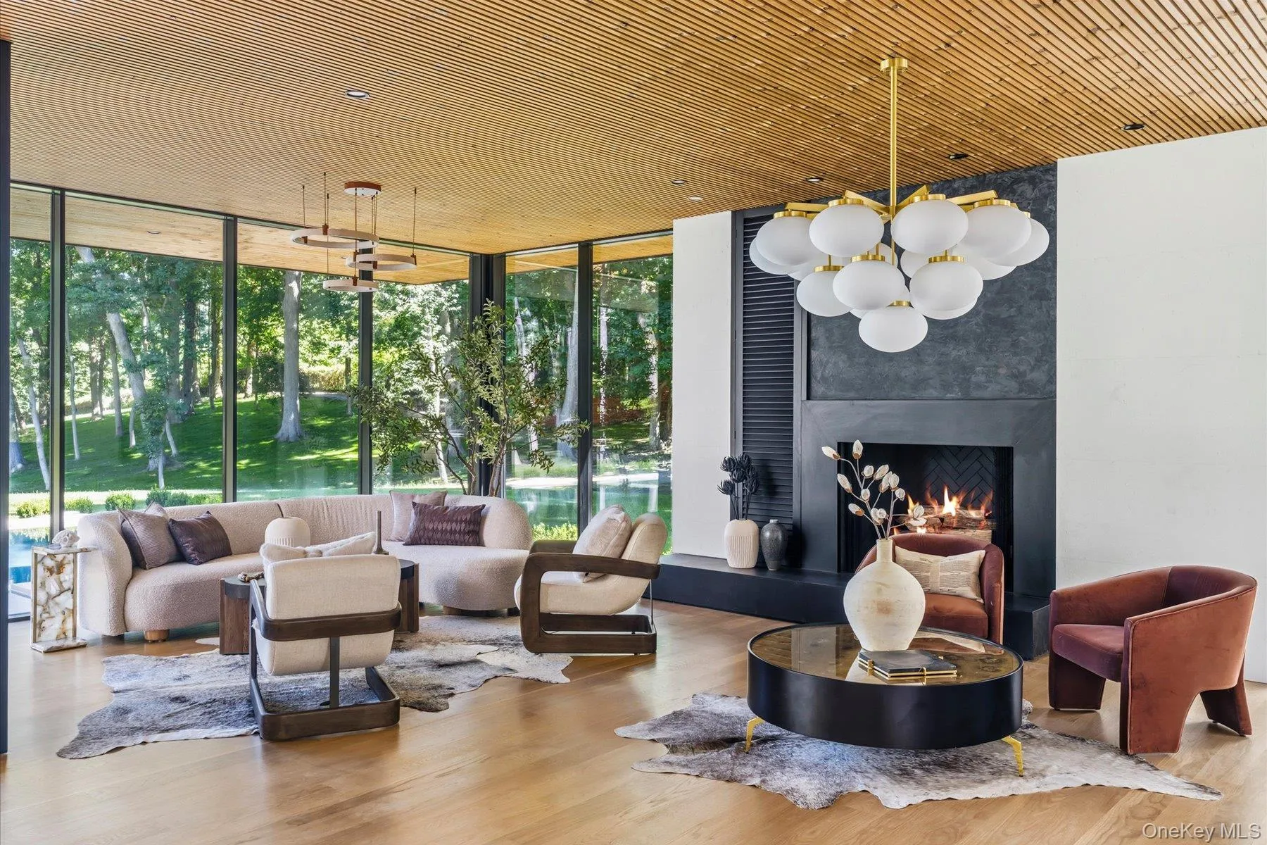 Great room with 10’ height and soaring glass walls and woodburning fireplace with water views Great room with 10’ height and soaring glass walls and woodburning fireplace with water views