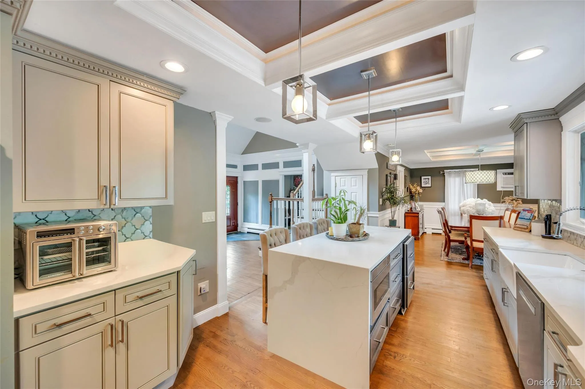 Kitchen featuring an oversized island with waterfall countertop, recessed lighting, and tray ceiling Kitchen featuring an oversized island with waterfall countertop, recessed lighting, and tray ceiling