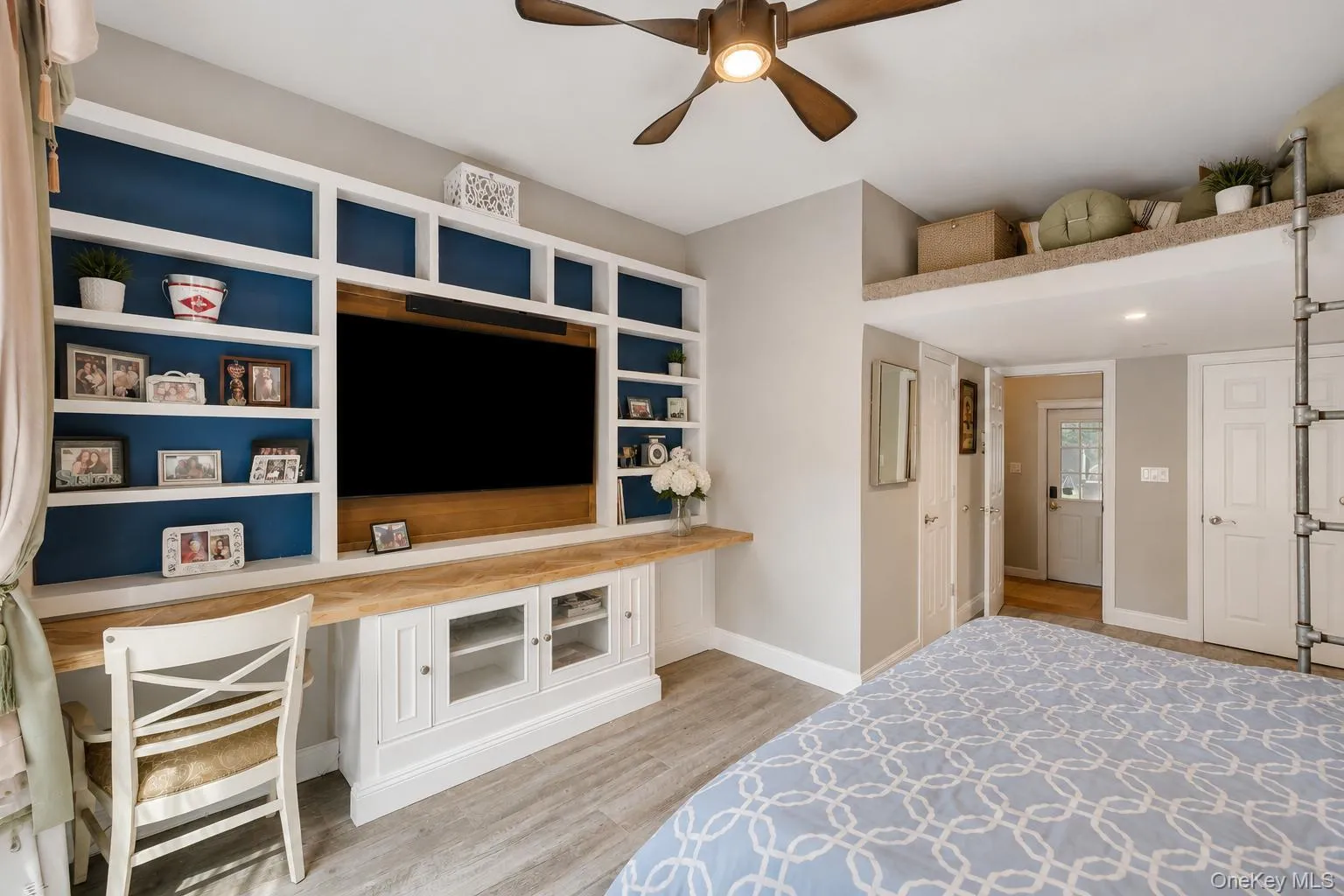 Custom built-in shelving with integrated media center, wood-finish flooring, recessed lighting, and a ceiling fan with light fixture Custom built-in shelving with integrated media center, wood-finish flooring, recessed lighting, and a ceiling fan with light fixture