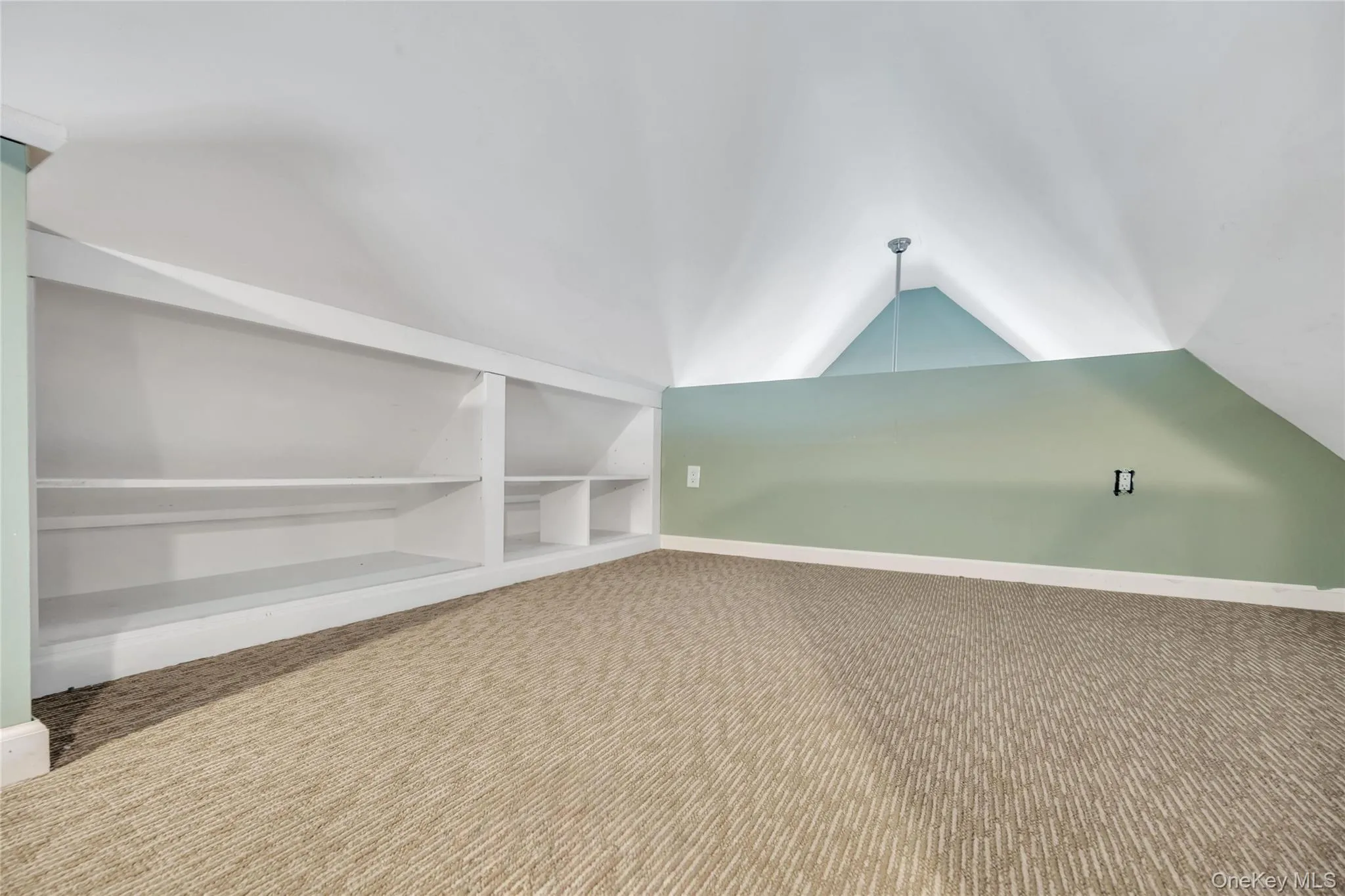 Vaulted ceiling with a recessed light fixture, built-in shelving, low-pile patterned carpeting, and painted accent walls Vaulted ceiling with a recessed light fixture, built-in shelving, low-pile patterned carpeting, and painted accent walls