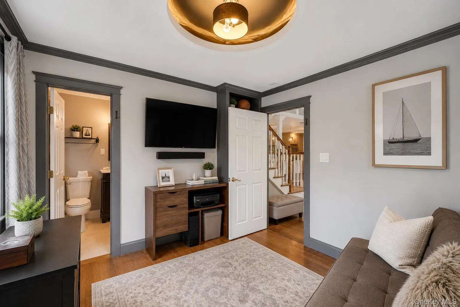 Interior space featuring dark wood-finish flooring, light grey walls with contrasting dark trim, and multiple windows providing natural illumination Interior space featuring dark wood-finish flooring, light grey walls with contrasting dark trim, and multiple windows providing natural illumination