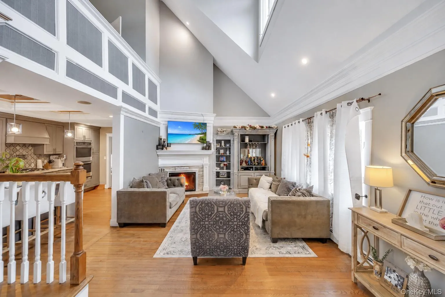 Vaulted ceiling living area featuring a stone surround fireplace, hardwood flooring, recessed lighting, and a built-in display cabinet Vaulted ceiling living area featuring a stone surround fireplace, hardwood flooring, recessed lighting, and a built-in display cabinet