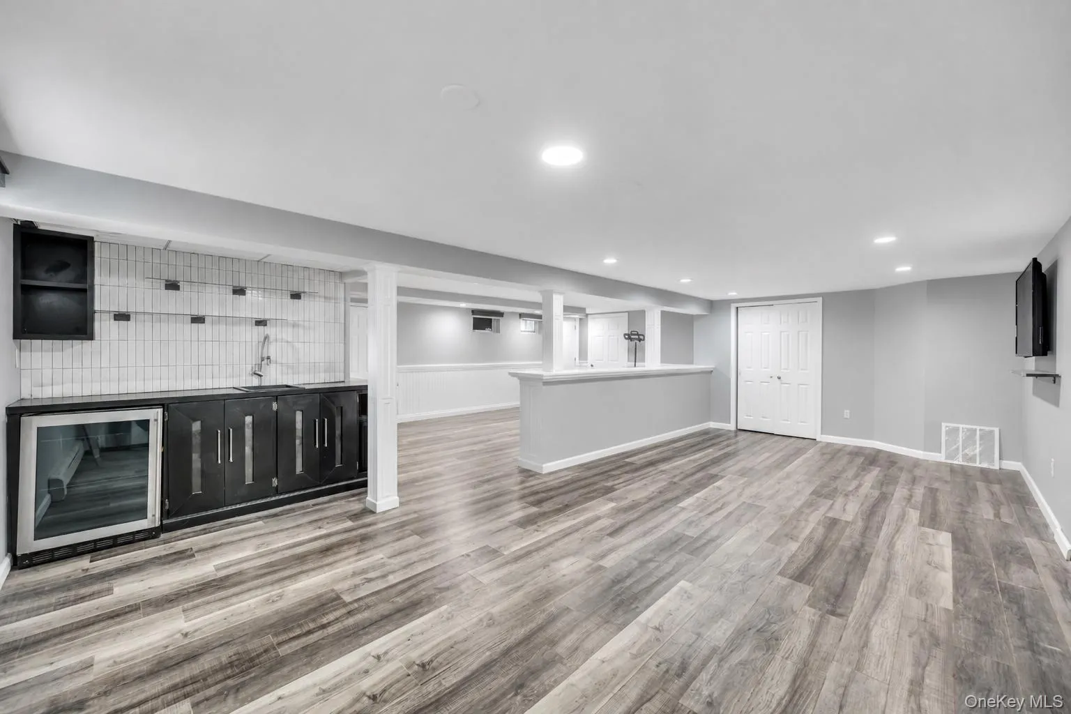 Spacious lower level featuring wood-finish flooring, recessed lighting, and a built-in wet bar with a beverage refrigerator Spacious lower level featuring wood-finish flooring, recessed lighting, and a built-in wet bar with a beverage refrigerator