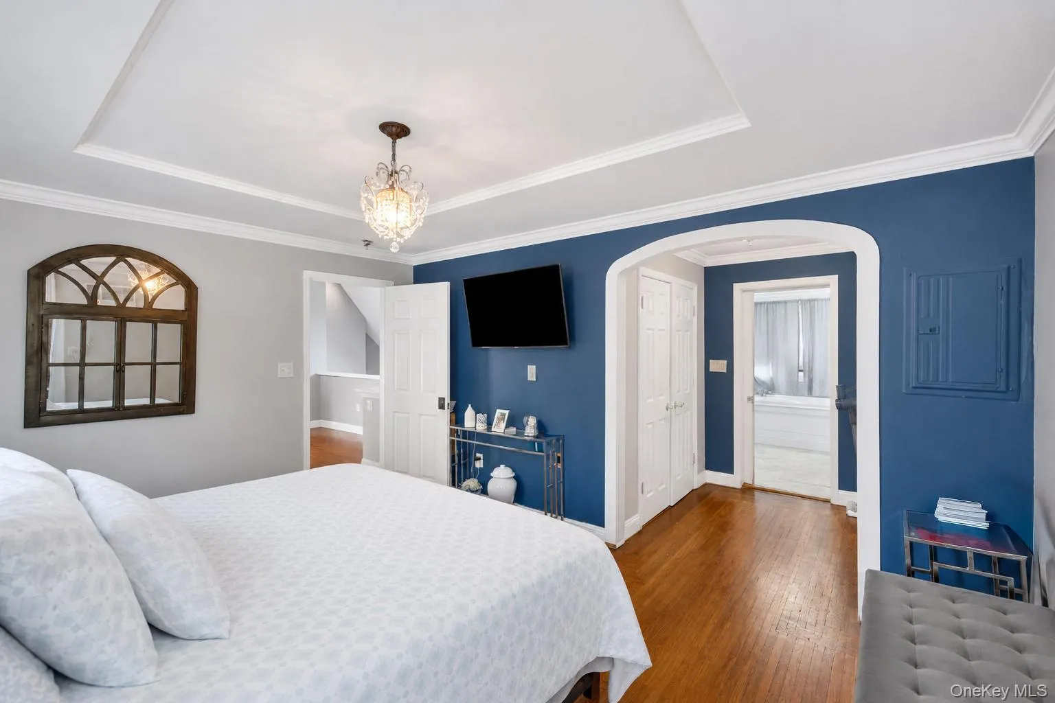Bedroom featuring wood-finish flooring, a tray ceiling, and crown molding Bedroom featuring wood-finish flooring, a tray ceiling, and crown molding