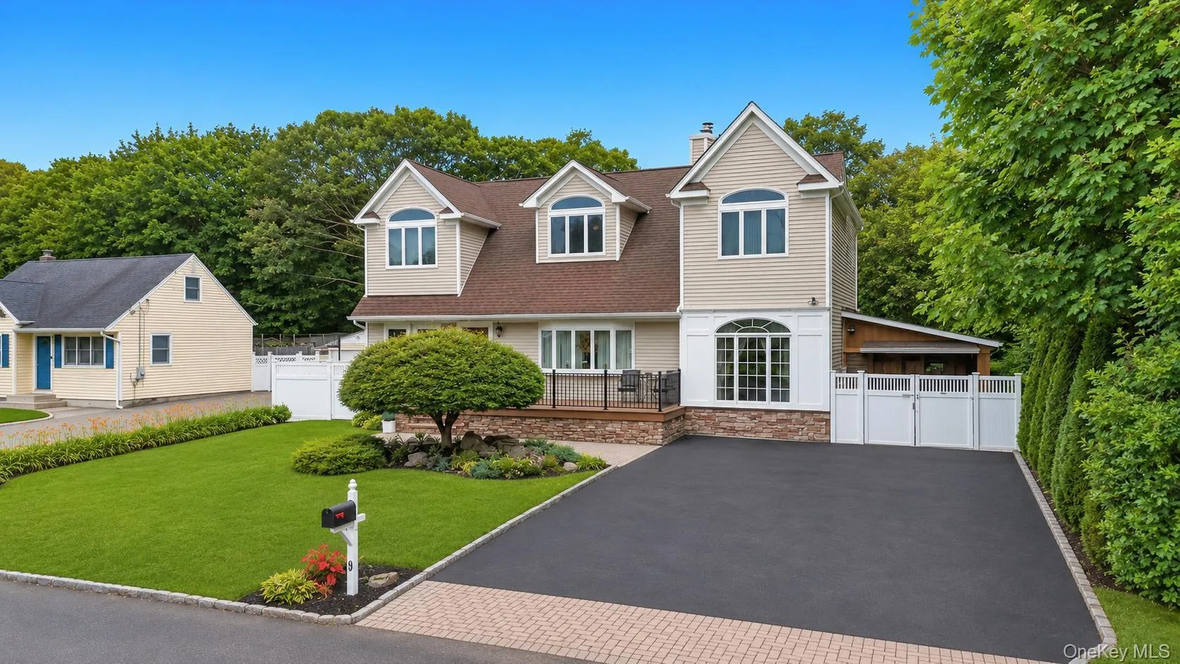 Modern residence featuring dormer windows, a driveway, and a manicured lawn Modern residence featuring dormer windows, a driveway, and a manicured lawn