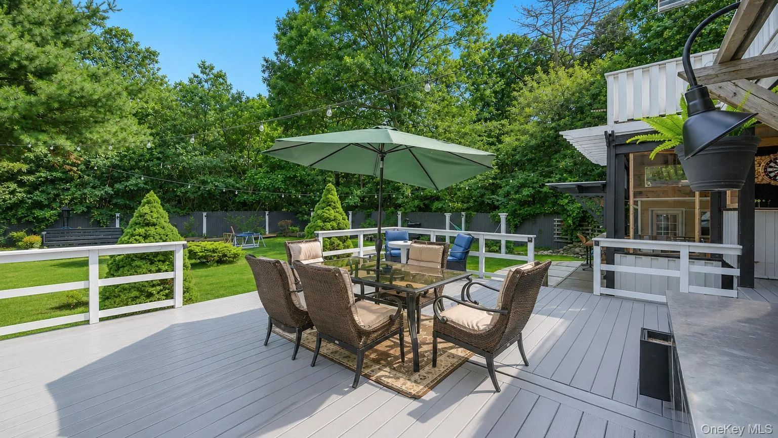 Expansive light-gray decking with white railings, featuring a glass-top dining table with wicker chairs Expansive light-gray decking with white railings, featuring a glass-top dining table with wicker chairs