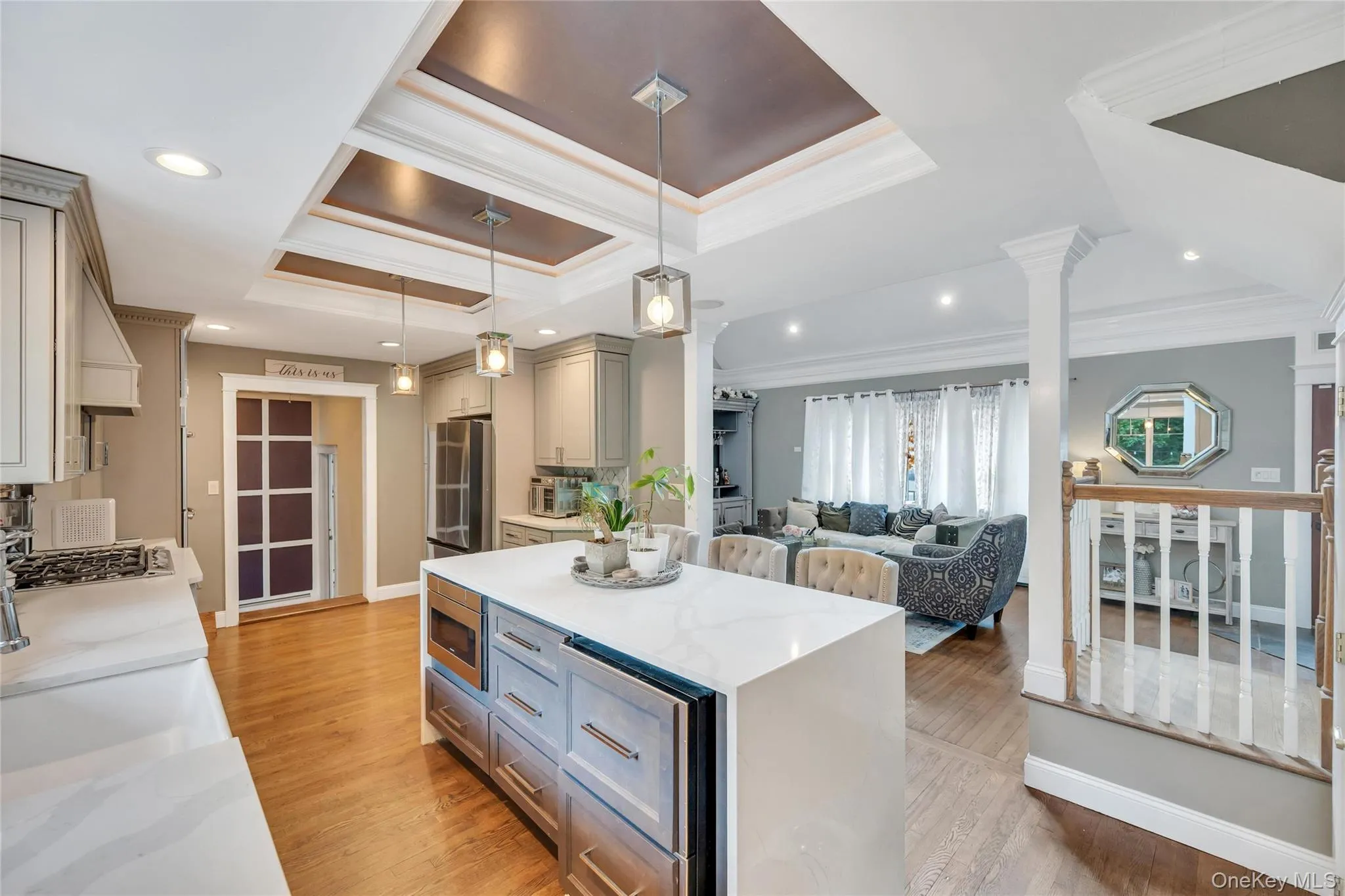 Spacious open-concept kitchen featuring light-toned cabinetry, a waterfall-edge island with an integrated microwave, quartz countertops, and recessed ceiling lighting Spacious open-concept kitchen featuring light-toned cabinetry, a waterfall-edge island with an integrated microwave, quartz countertops, and recessed ceiling lighting