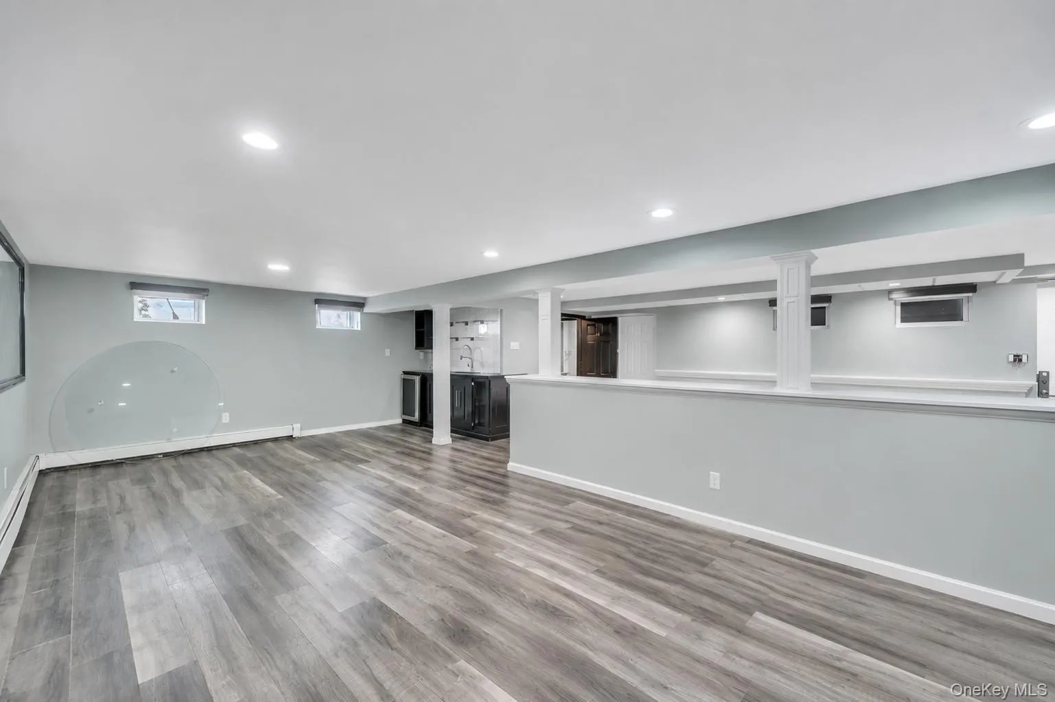 Spacious lower level featuring wood-finish flooring, recessed lighting, and a built-in wet bar with a beverage refrigerator Spacious lower level featuring wood-finish flooring, recessed lighting, and a built-in wet bar with a beverage refrigerator