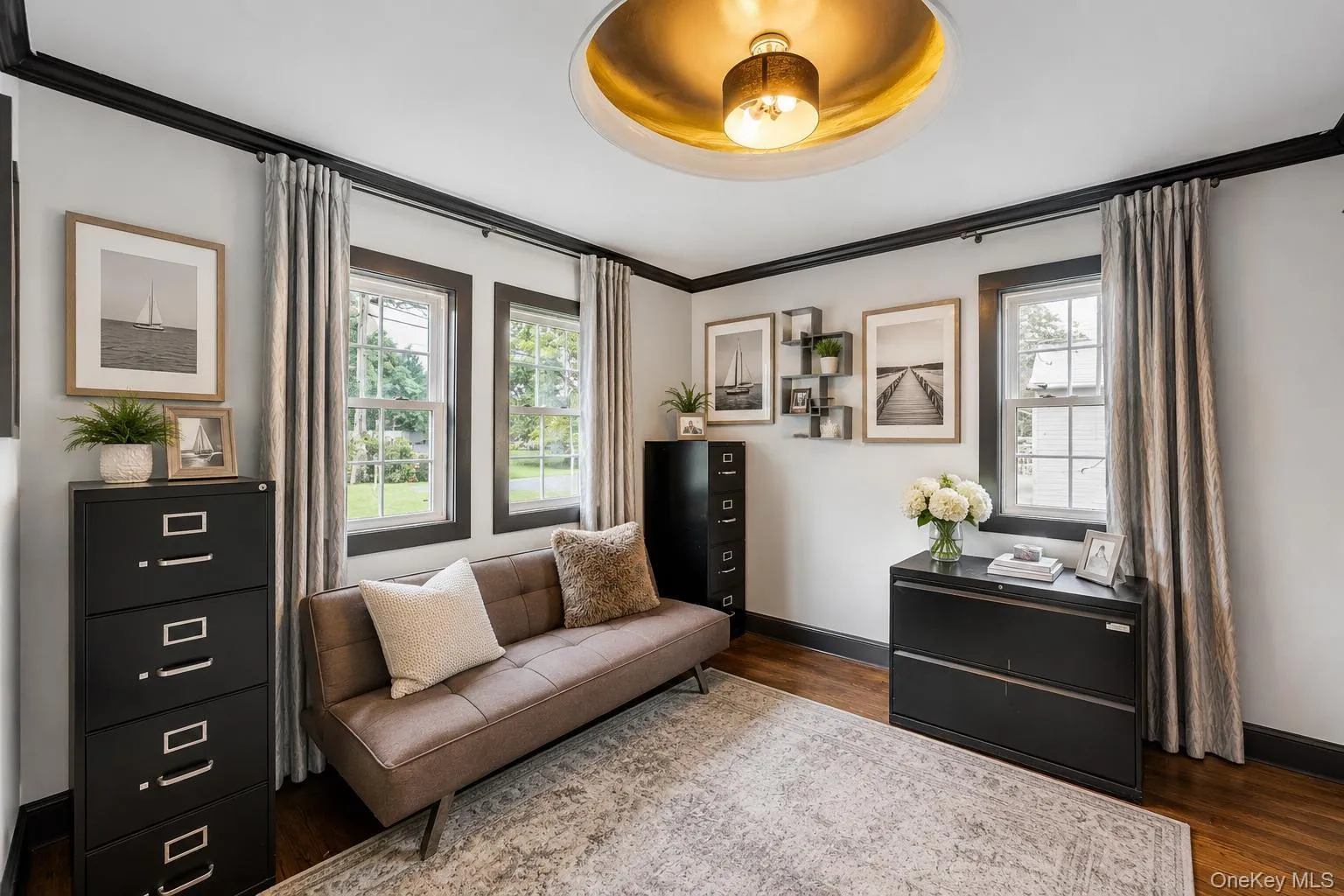Interior space featuring dark wood-finish flooring, light grey walls with contrasting dark trim, and multiple windows providing natural illumination Interior space featuring dark wood-finish flooring, light grey walls with contrasting dark trim, and multiple windows providing natural illumination