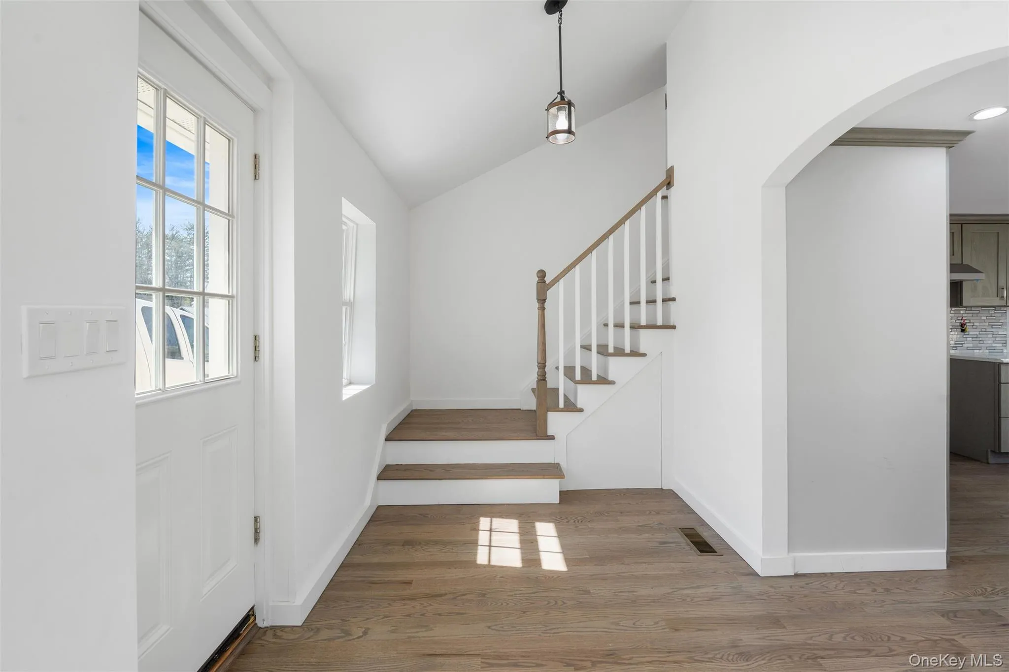 Entrance foyer with wood finished floors, arched walkways, stairs, and lofted ceiling Entrance foyer with wood finished floors, arched walkways, stairs, and lofted ceiling