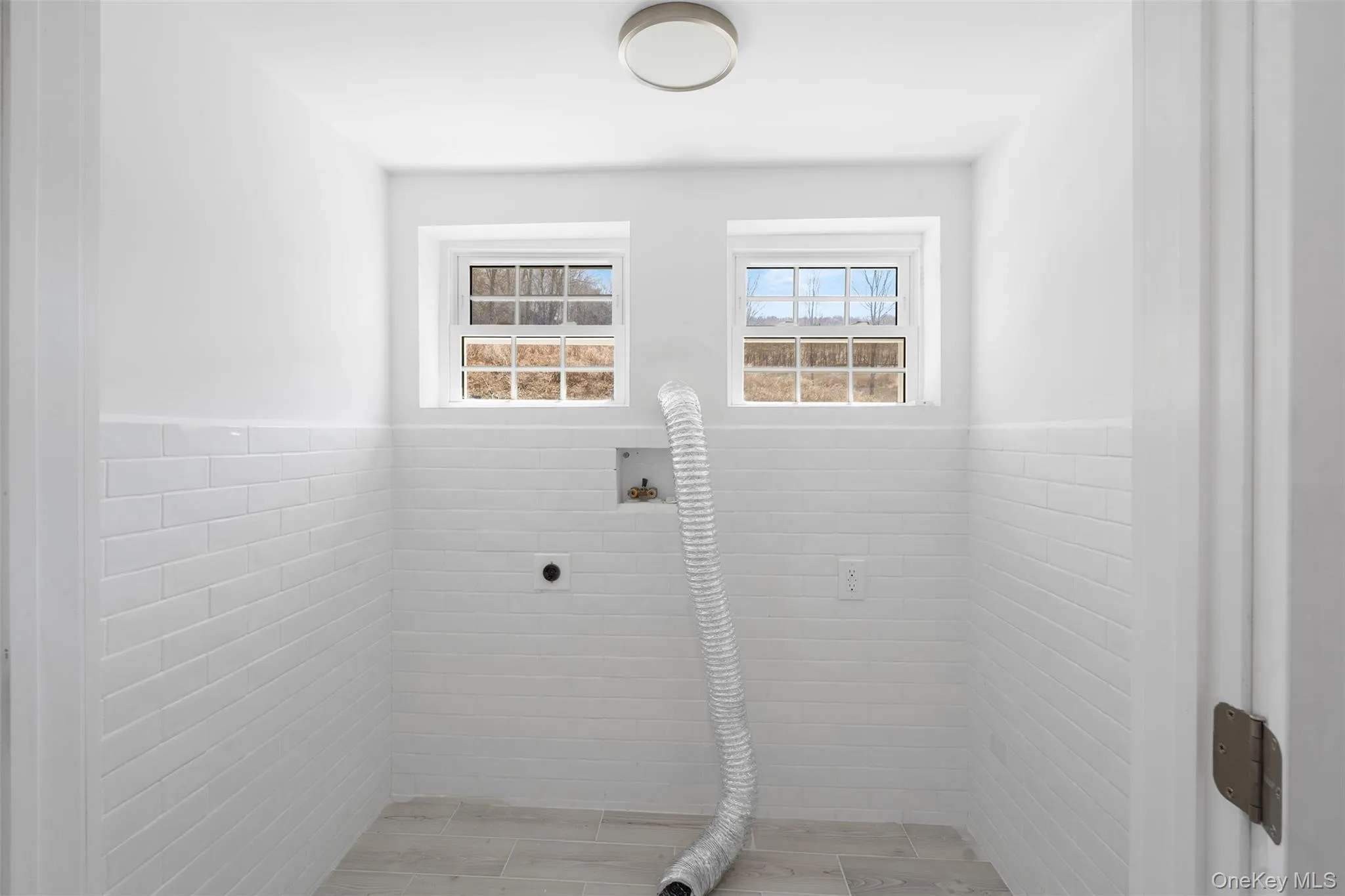 Laundry area featuring hookup for an electric dryer, tile walls, and a wainscoted wall Laundry area featuring hookup for an electric dryer, tile walls, and a wainscoted wall