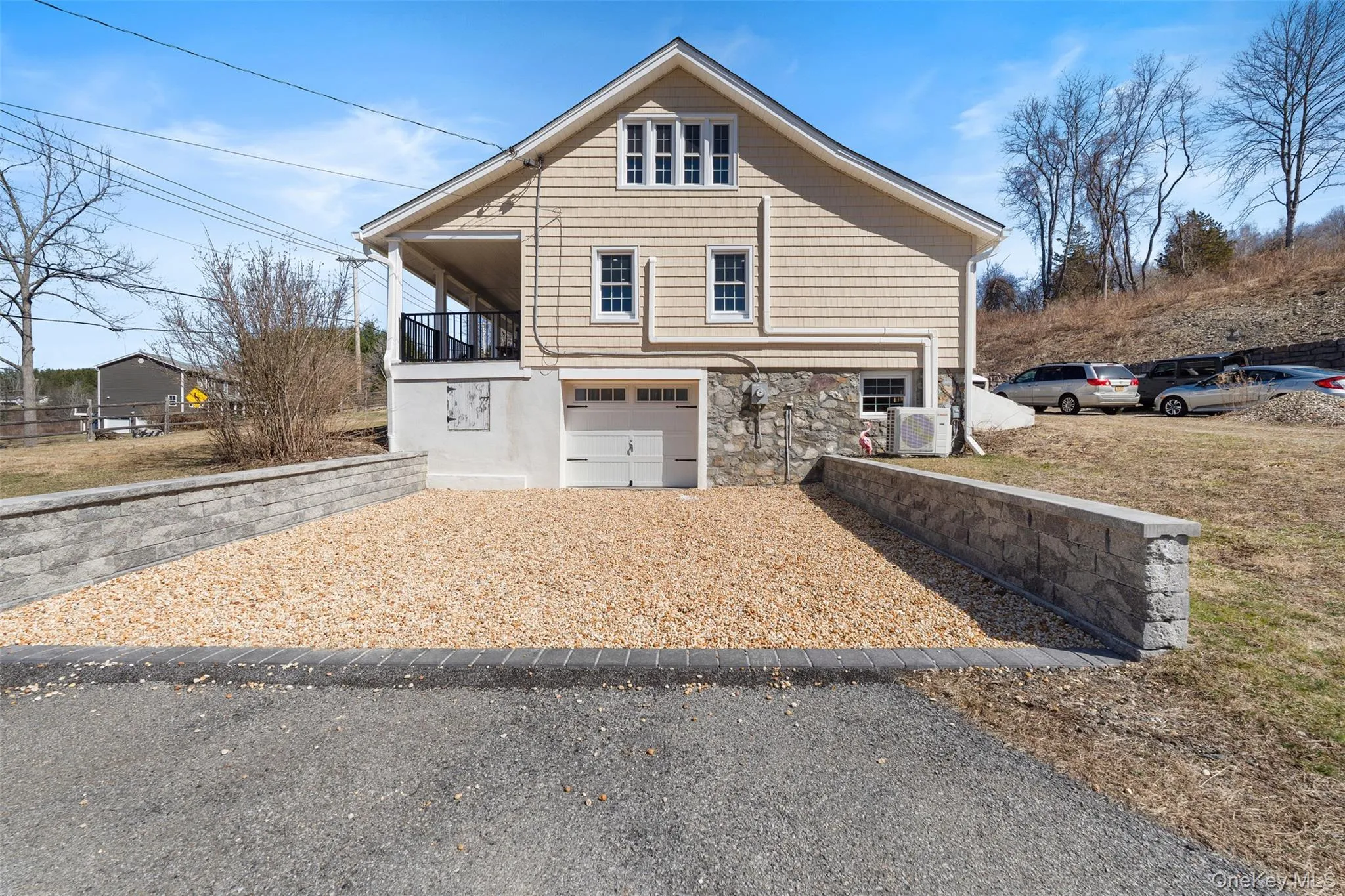 View of home's exterior featuring stone siding, an attached garage, and gravel driveway View of home's exterior featuring stone siding, an attached garage, and gravel driveway