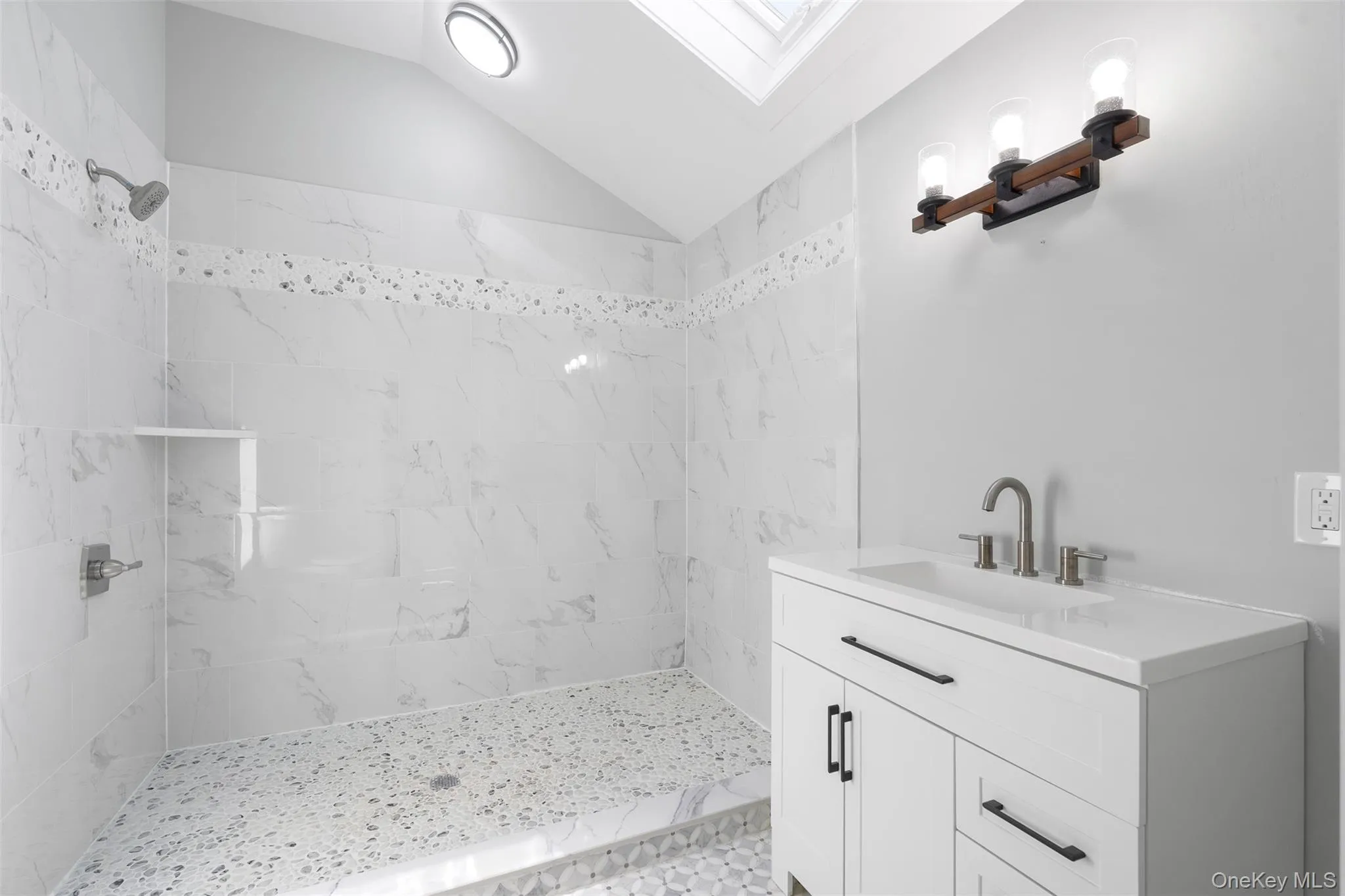 Bathroom with a skylight, a tile shower, lofted ceiling, and vanity Bathroom with a skylight, a tile shower, lofted ceiling, and vanity