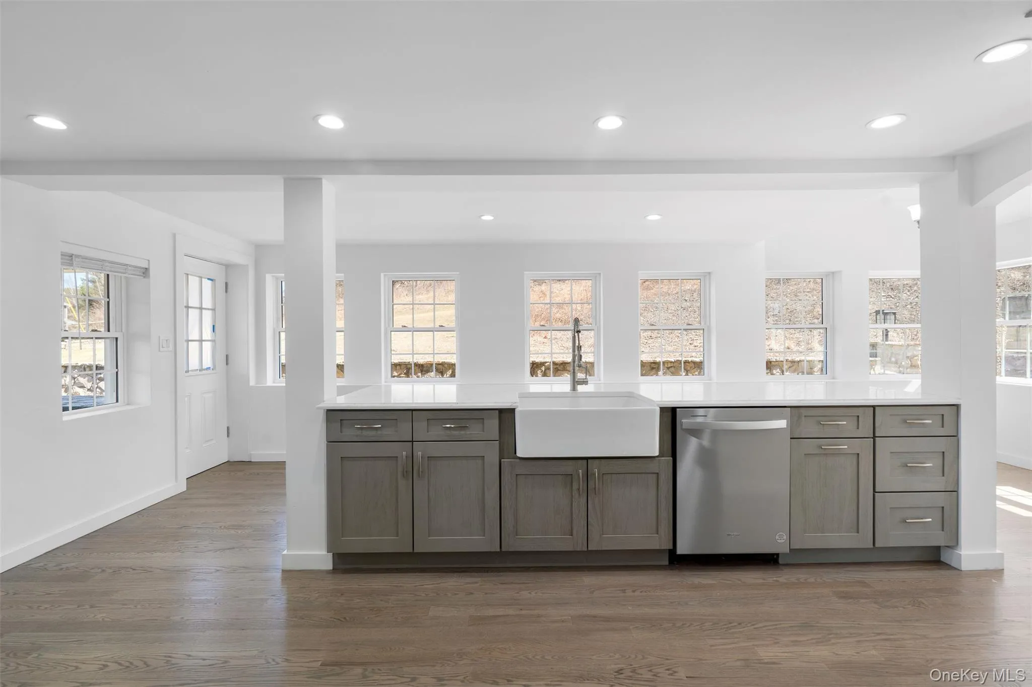 Kitchen featuring dishwasher, dark wood finished floors, light countertops, recessed lighting, and gray cabinets Kitchen featuring dishwasher, dark wood finished floors, light countertops, recessed lighting, and gray cabinets