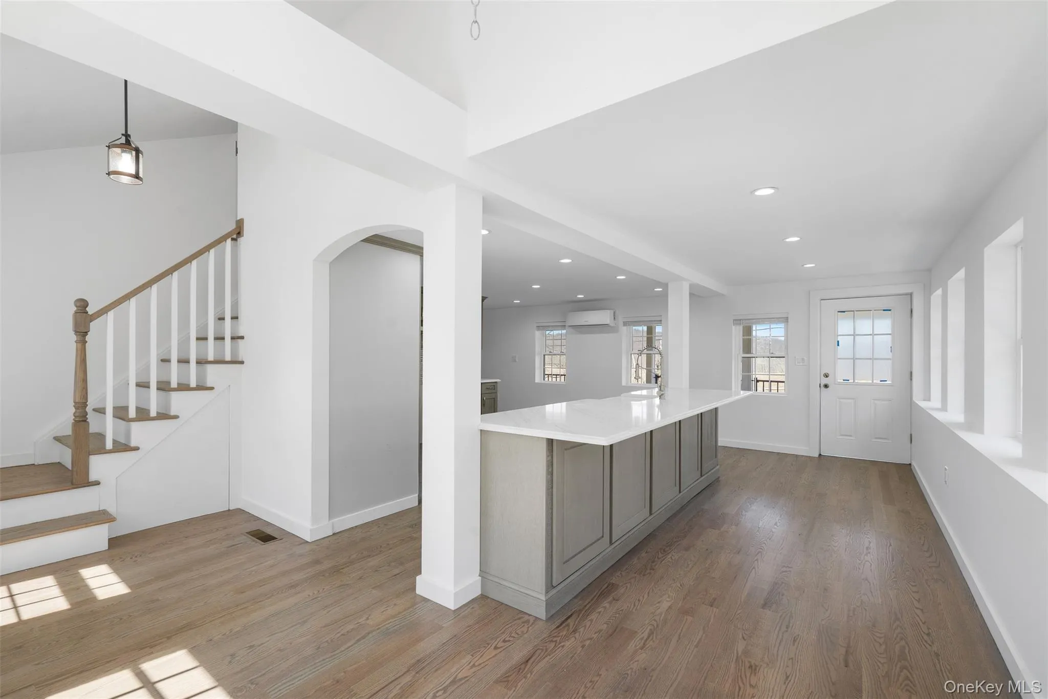 Kitchen featuring an AC wall unit, gray cabinets, wood finished floors, light countertops, and recessed lighting Kitchen featuring an AC wall unit, gray cabinets, wood finished floors, light countertops, and recessed lighting