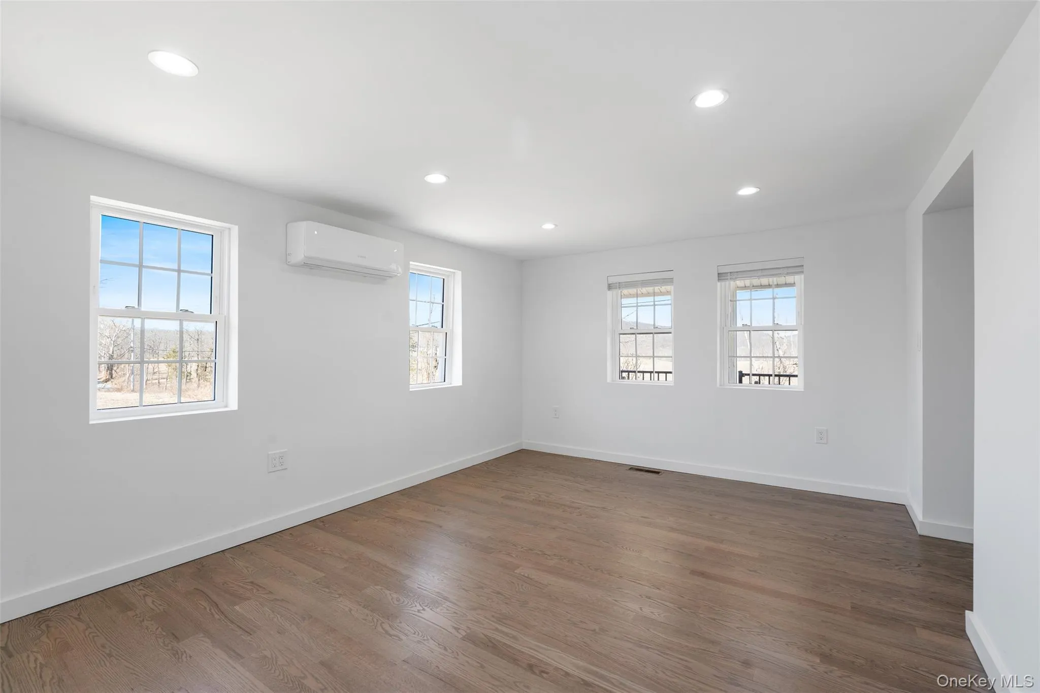 Unfurnished room featuring a wall mounted air conditioner, healthy amount of natural light, recessed lighting, and wood finished floors Unfurnished room featuring a wall mounted air conditioner, healthy amount of natural light, recessed lighting, and wood finished floors