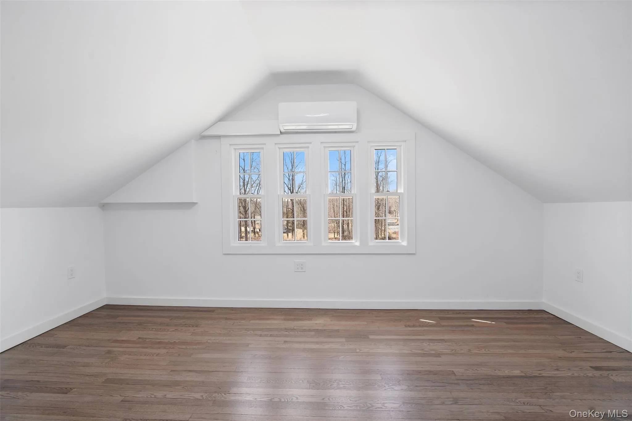 Bonus room featuring a wall mounted AC, lofted ceiling, and wood finished floors Bonus room featuring a wall mounted AC, lofted ceiling, and wood finished floors
