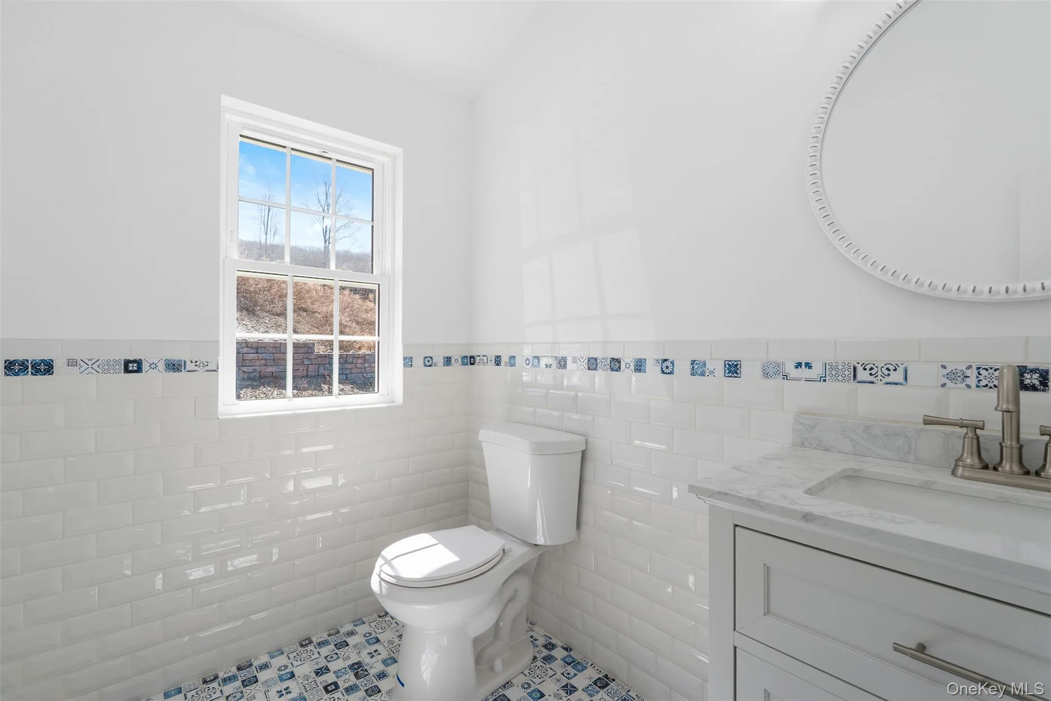 Half bathroom featuring tile walls, wainscoting, tile patterned floors, and vanity Half bathroom featuring tile walls, wainscoting, tile patterned floors, and vanity