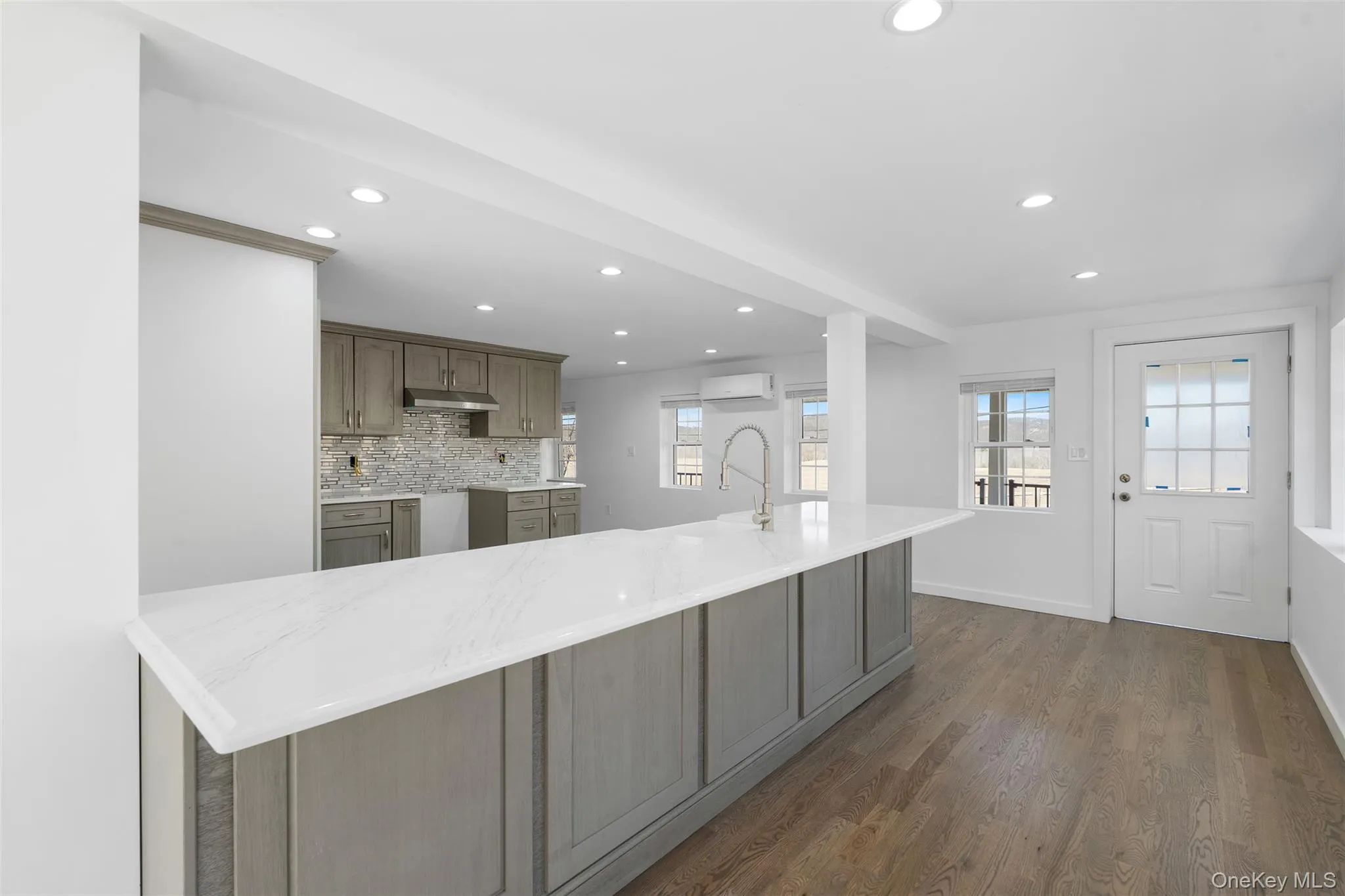 Kitchen featuring recessed lighting, a wall unit AC, dark wood-type flooring, under cabinet range hood, and backsplash Kitchen featuring recessed lighting, a wall unit AC, dark wood-type flooring, under cabinet range hood, and backsplash
