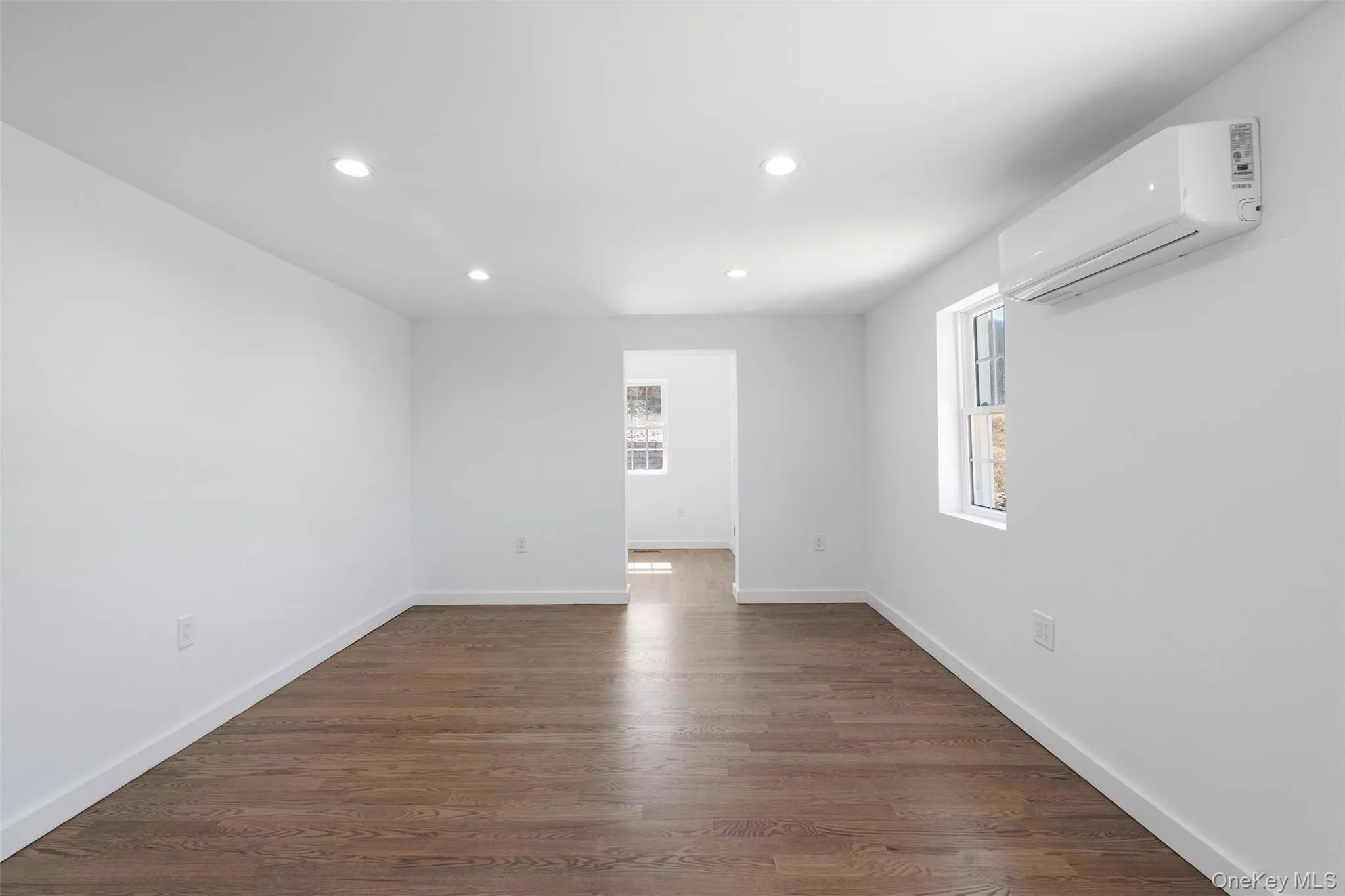 Unfurnished room with a wall mounted AC, recessed lighting, and dark wood-type flooring Unfurnished room with a wall mounted AC, recessed lighting, and dark wood-type flooring