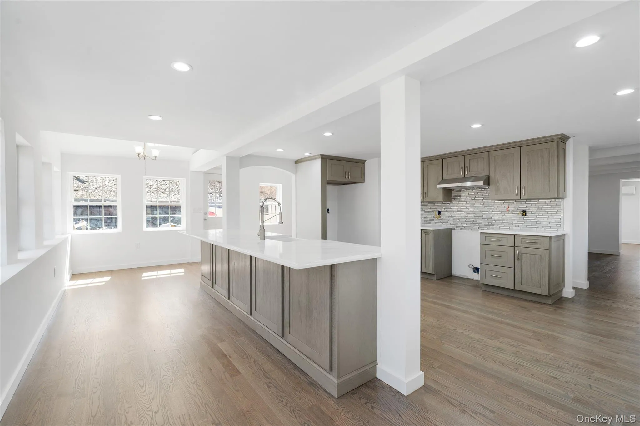Kitchen with under cabinet range hood, a chandelier, light wood-style floors, tasteful backsplash, and recessed lighting Kitchen with under cabinet range hood, a chandelier, light wood-style floors, tasteful backsplash, and recessed lighting