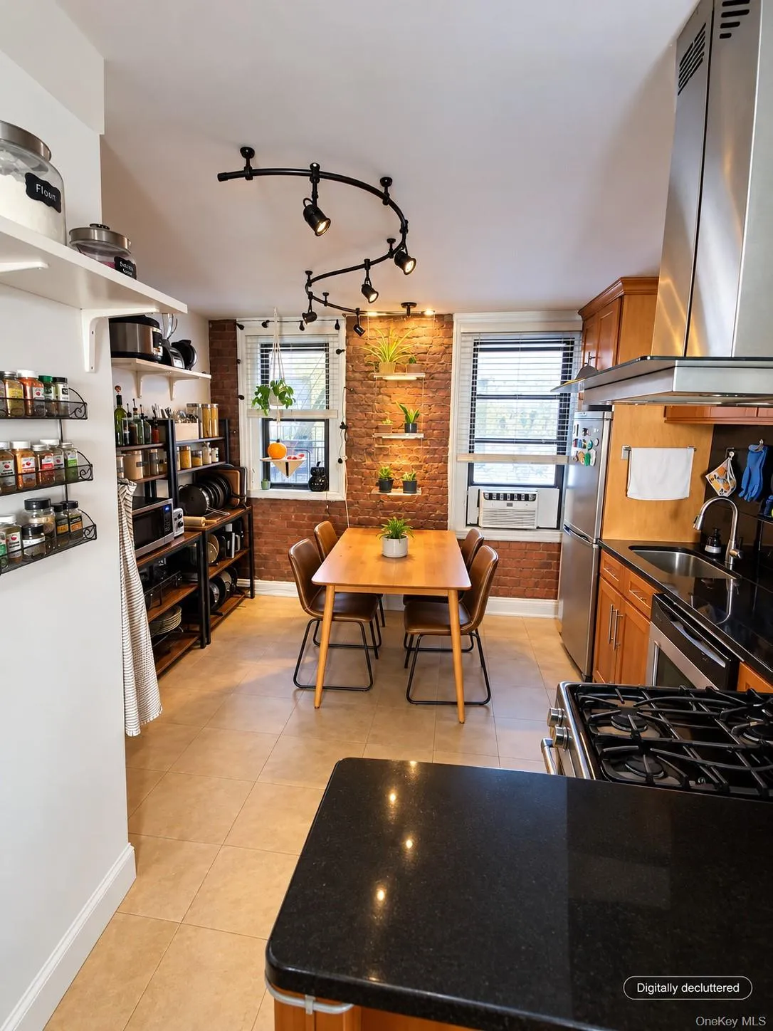 Exposed brick accent wall, track lighting, stainless steel appliances, solid surface countertops, and tile flooring Exposed brick accent wall, track lighting, stainless steel appliances, solid surface countertops, and tile flooring