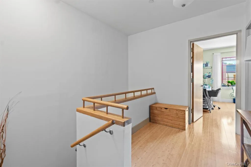 Hallway featuring light wood-type flooring, an office area, and baseboards Hallway featuring light wood-type flooring, an office area, and baseboards