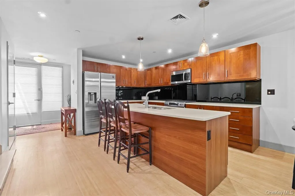Kitchen featuring stainless steel appliances, light wood-style flooring, a sink, a kitchen bar, and recessed lighting Kitchen featuring stainless steel appliances, light wood-style flooring, a sink, a kitchen bar, and recessed lighting