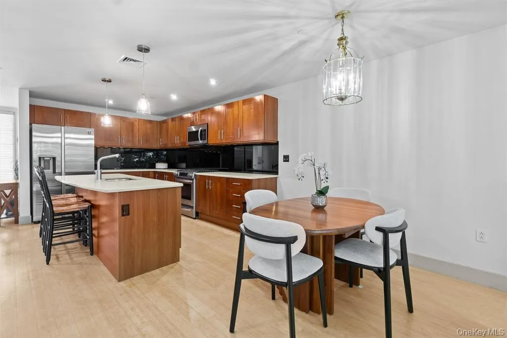 Kitchen featuring appliances with stainless steel finishes, a sink, decorative backsplash, light wood-style flooring, and pendant lighting Kitchen featuring appliances with stainless steel finishes, a sink, decorative backsplash, light wood-style flooring, and pendant lighting