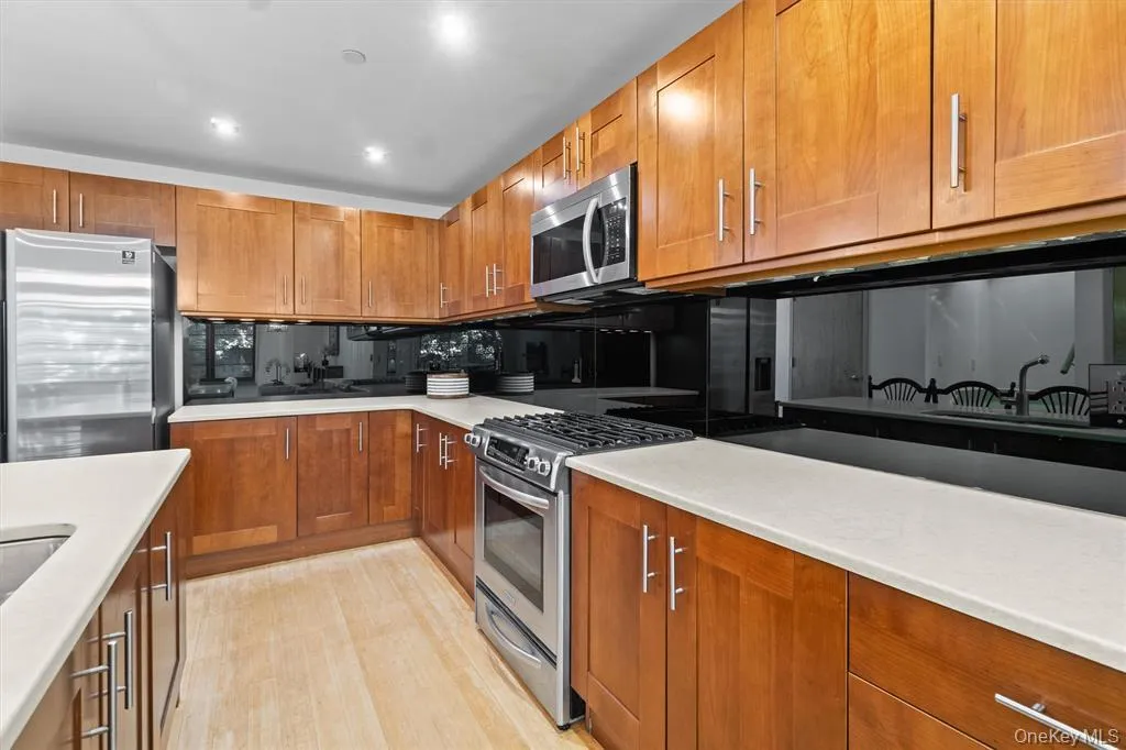 Kitchen with stainless steel appliances, brown cabinets, tasteful backsplash, light countertops, and recessed lighting Kitchen with stainless steel appliances, brown cabinets, tasteful backsplash, light countertops, and recessed lighting