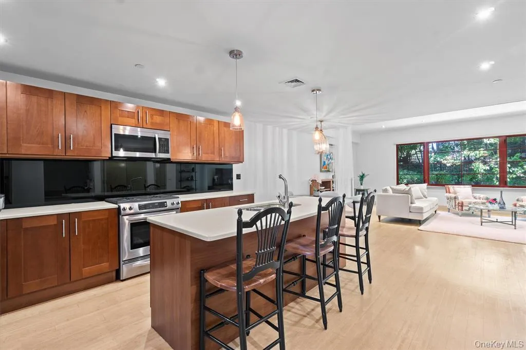 Kitchen featuring stainless steel appliances, a sink, light countertops, brown cabinetry, and light wood-type flooring Kitchen featuring stainless steel appliances, a sink, light countertops, brown cabinetry, and light wood-type flooring