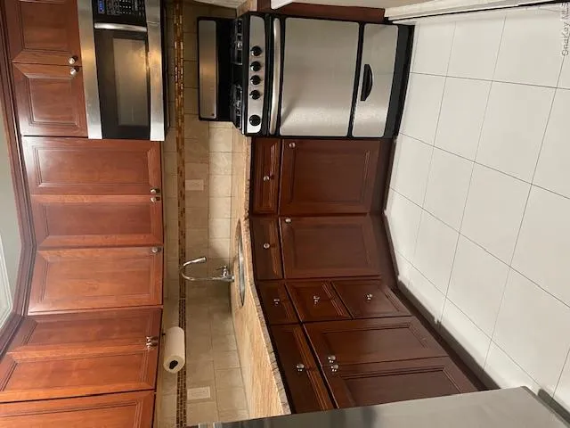 Kitchen with stainless steel microwave, stove, light tile patterned floors, decorative backsplash, and light stone countertops Kitchen with stainless steel microwave, stove, light tile patterned floors, decorative backsplash, and light stone countertops