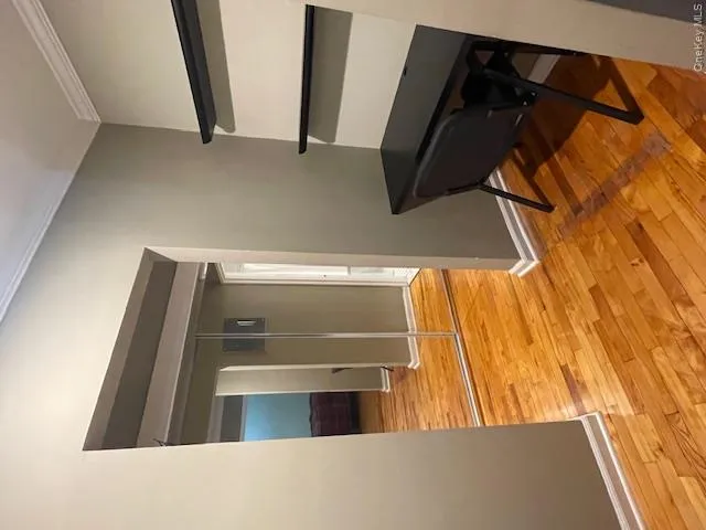 Corridor featuring light wood-style flooring, ornamental molding, and an office area Corridor featuring light wood-style flooring, ornamental molding, and an office area