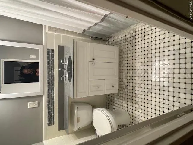 Bathroom with light tile patterned flooring, tile walls, vanity, and a wainscoted wall Bathroom with light tile patterned flooring, tile walls, vanity, and a wainscoted wall