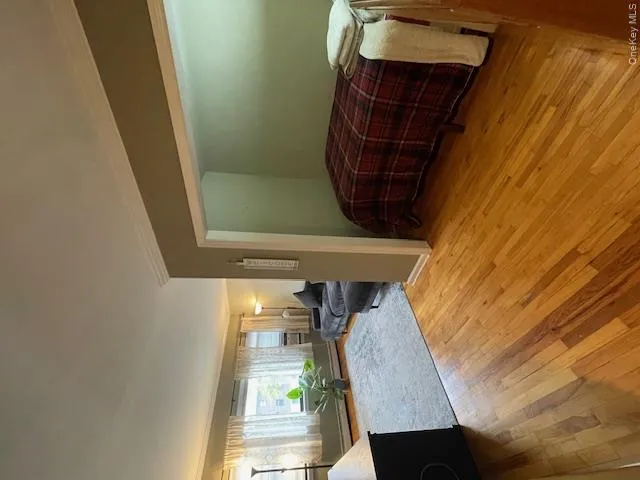 Bedroom featuring light wood-style flooring, ornamental molding, and a baseboard radiator Bedroom featuring light wood-style flooring, ornamental molding, and a baseboard radiator